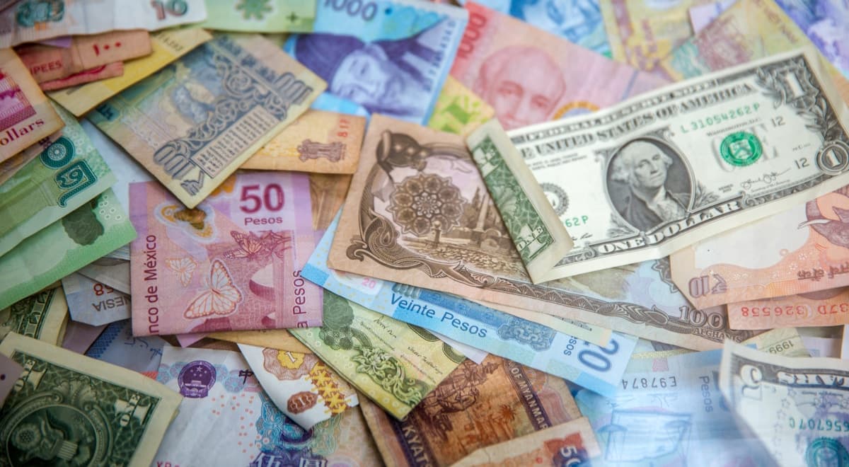 Billetes de pesos mexicanos y dólares americanos junto a una calculadora